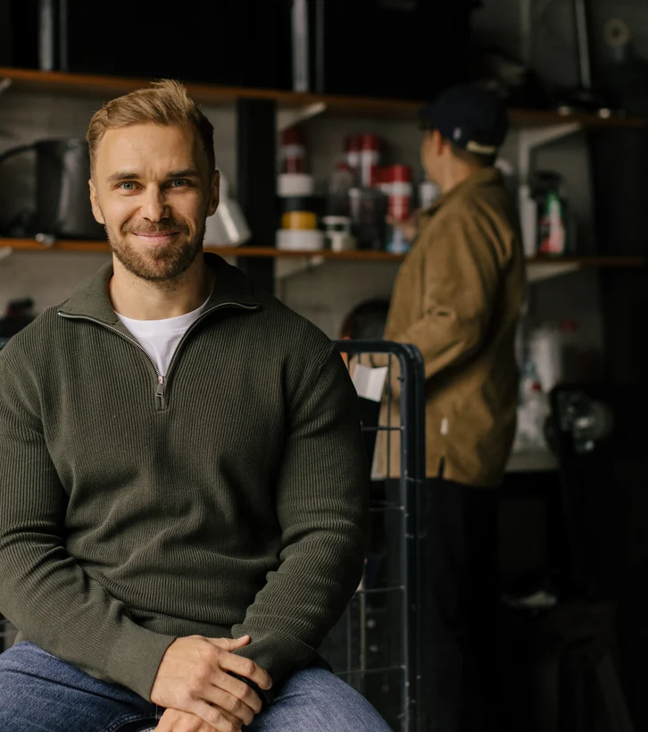 Man seated with a colleague working in the workshop behind him